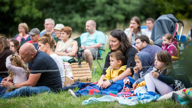 Audience members enjoying an open-air theatre performance in the garden at Shugborough Estate, Staffordshire